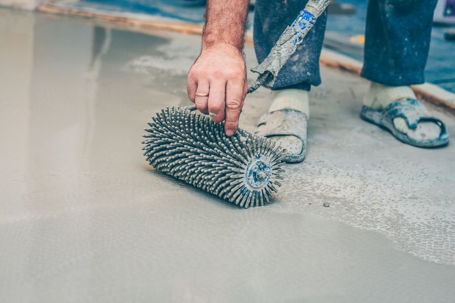 Roller opening the surface of a New Orleans concrete slab before coating