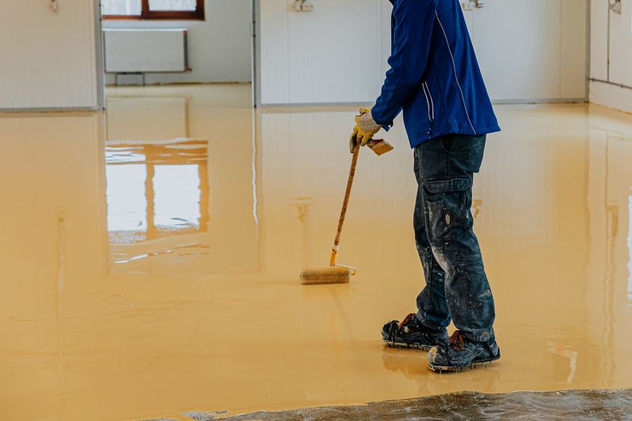 Contractor spreading an epoxy floor coating across a concrete floor