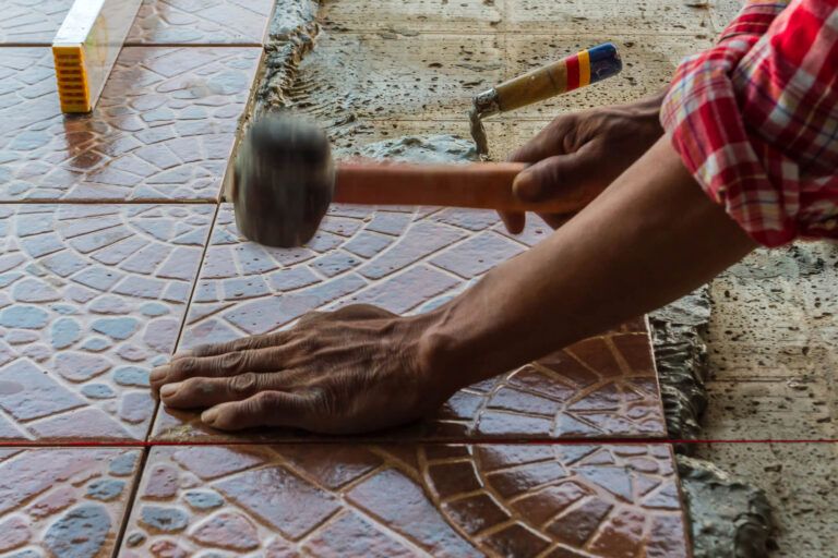 Floor tiles being tapped into place with a rubber mallet