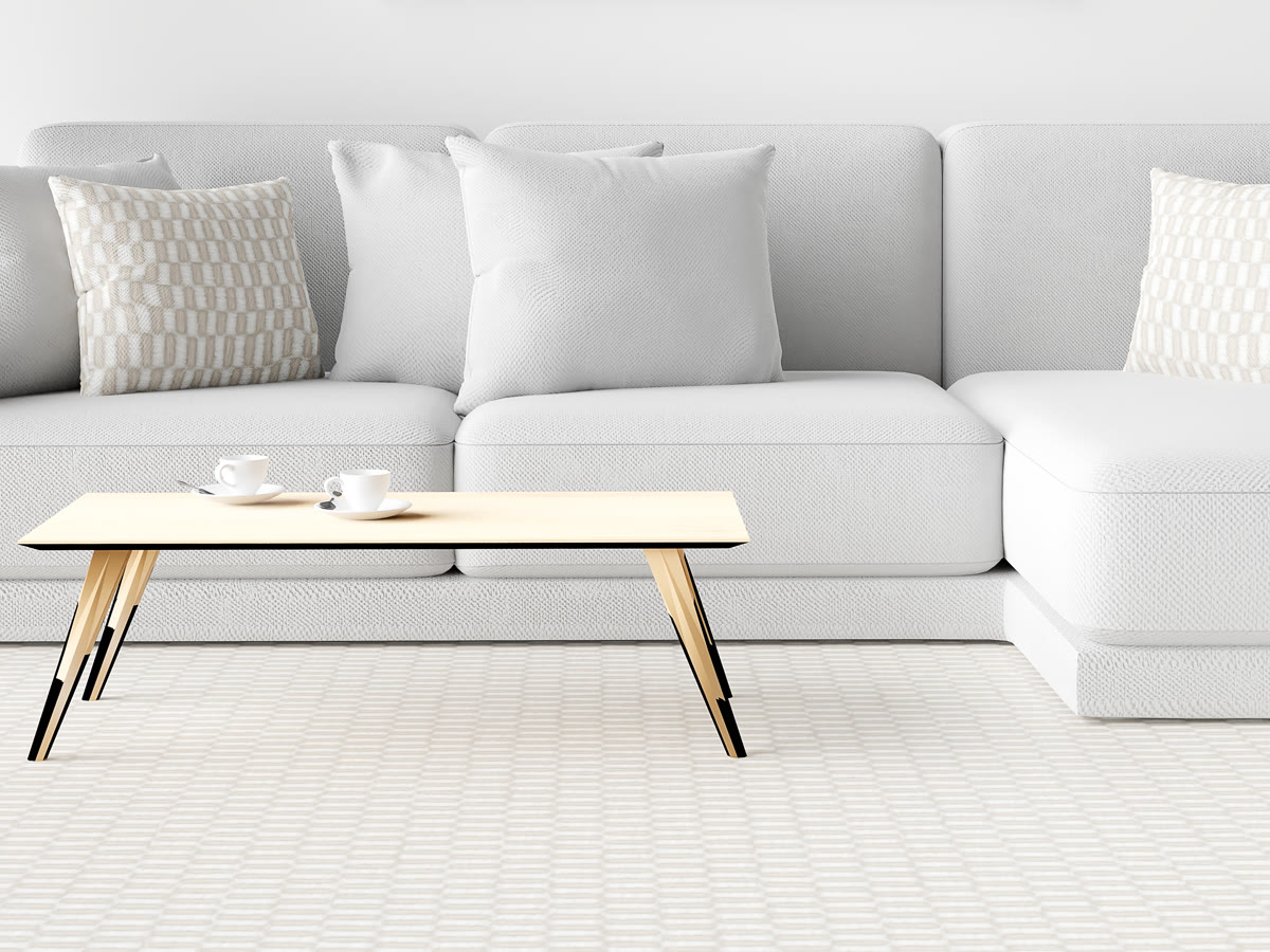 Pale wall-to-wall carpet running under a sofa in a bright room
